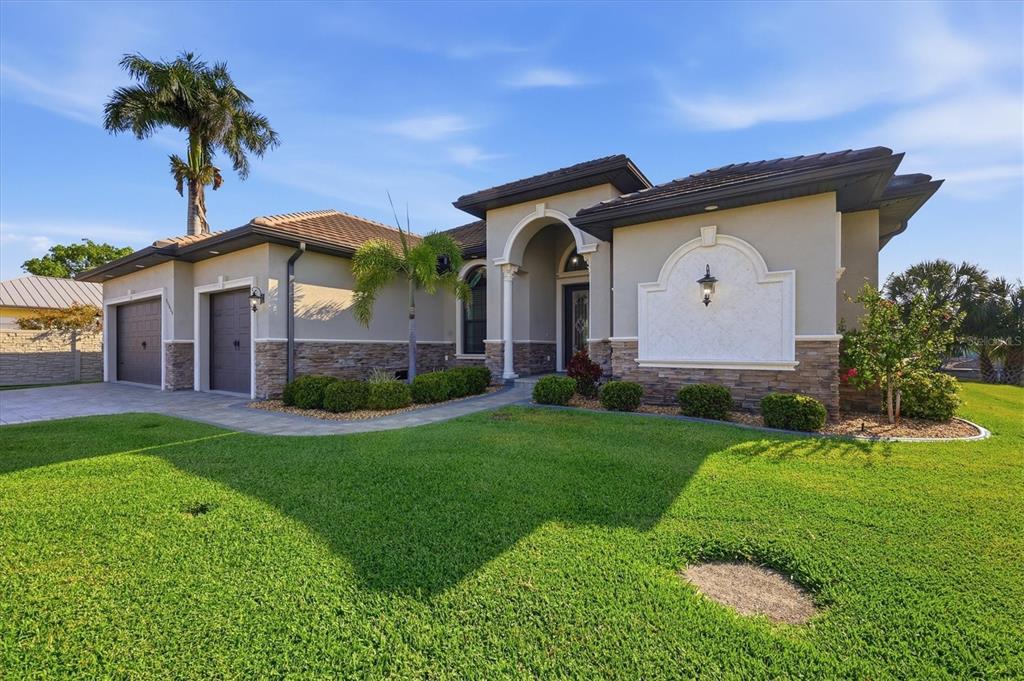 A single-story house with a stone facade, two-car garage, and a manicured front lawn — 14654 SAN DOMINGO BOULEVARD, PORT CHARLOTTE, FL