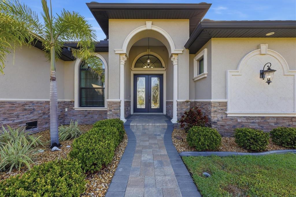 The front exterior of a house features a stone-accented facade, arched entryway, and paved walkway — 14654 SAN DOMINGO BOULEVARD, PORT CHARLOTTE, FL