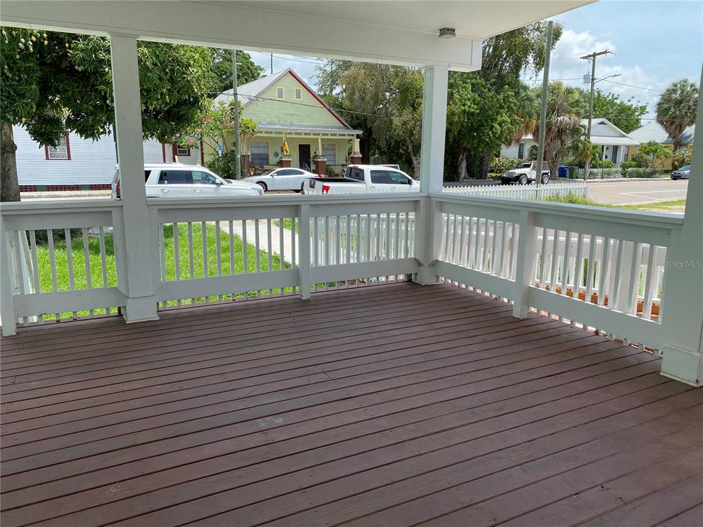 A wooden porch with white railings overlooks a street with houses and parked cars — 1411 N 17TH STREET, TAMPA, FL