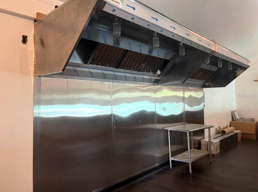 A commercial kitchen space features a large stainless steel exhaust hood and matching wall panels — 1411 N 17TH STREET, TAMPA, FL