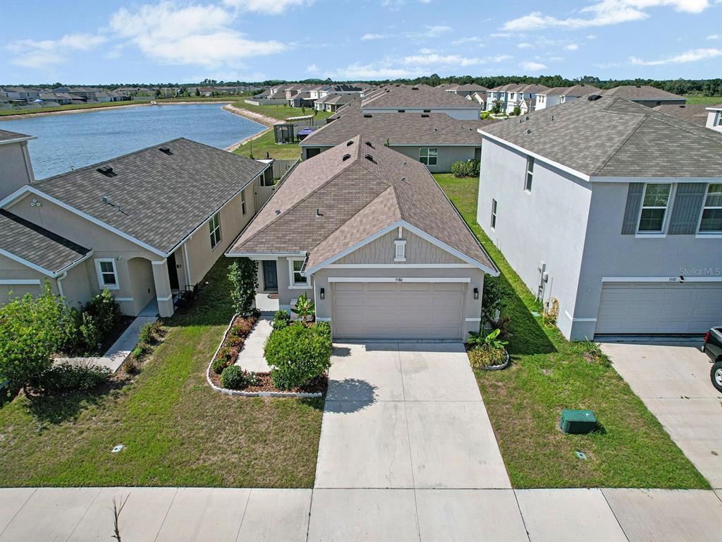 An aerial view shows a single-story suburban house with a two-car garage and driveway — 5586 LOGAN CAVE AVENUE, WIMAUMA, FL