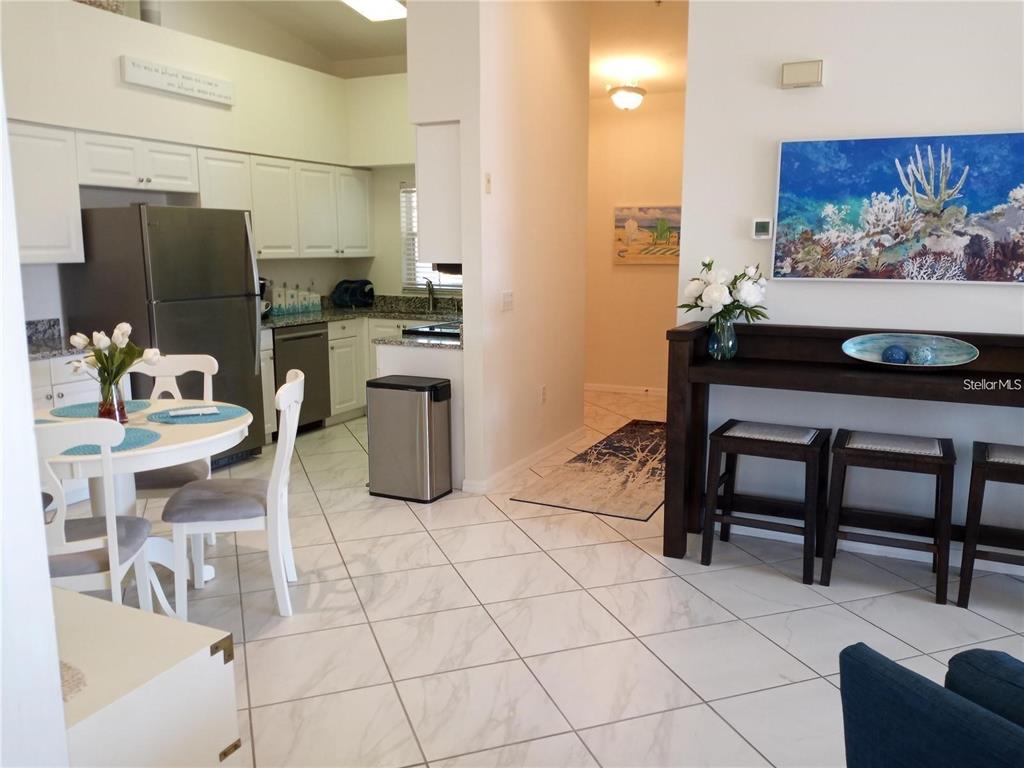 A kitchen with white cabinets and stainless steel appliances sits beside a dining area — 4216 CENTRAL SARASOTA PARKWAY UNIT 1325, SARASOTA, FL