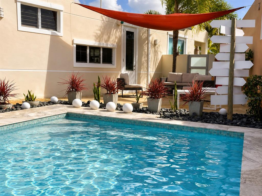 A backyard swimming pool features a patio area with lounge seating and a shade sail — Carr #3 SOLIMAR PATILLAS, PATILLAS, PR