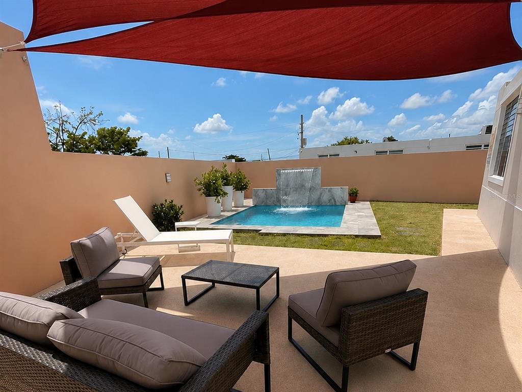 A patio features outdoor furniture, a small swimming pool with a waterfall, and a shade sail — Carr #3 SOLIMAR PATILLAS, PATILLAS, PR