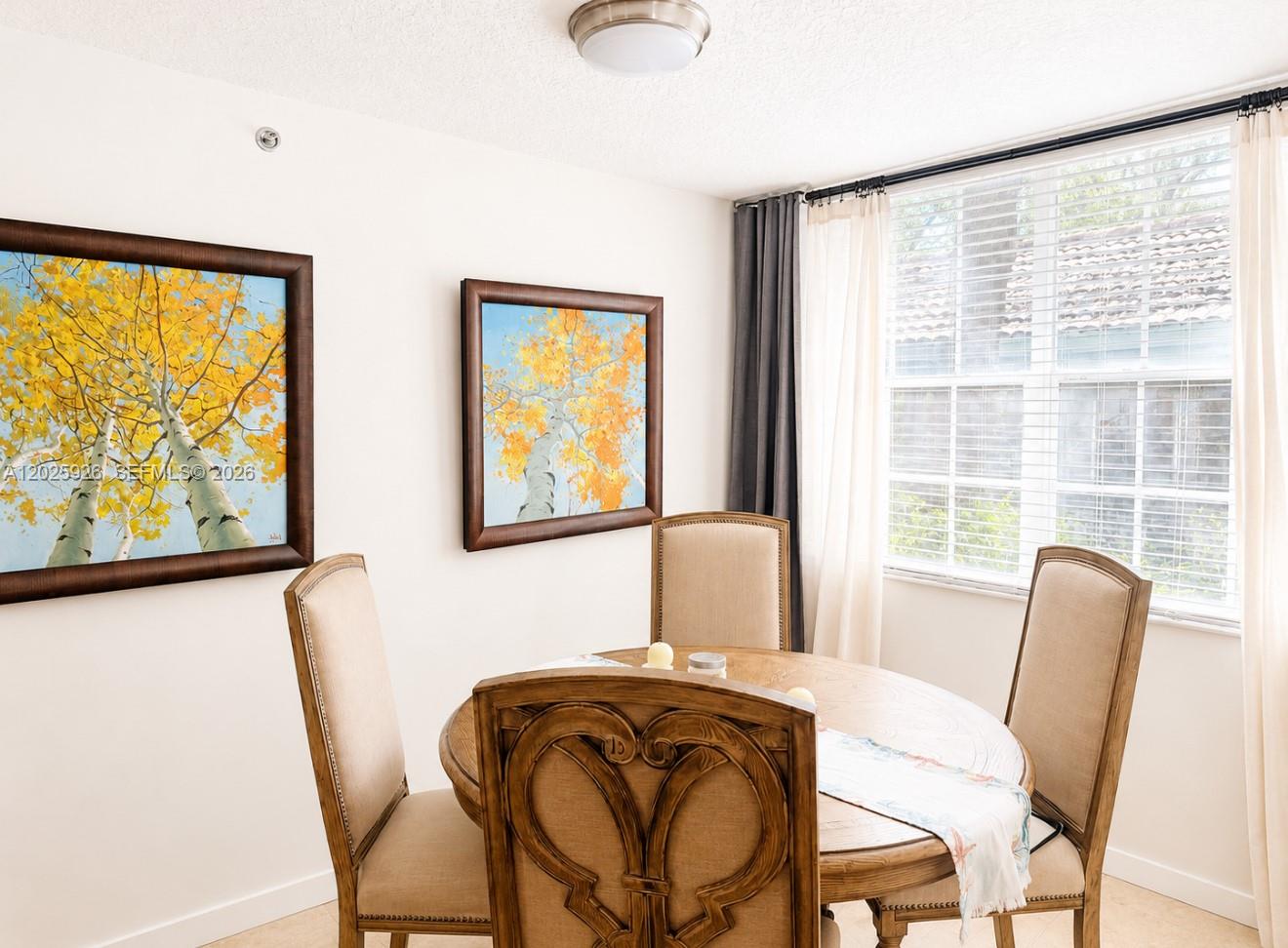 A dining area features a round wooden table, four upholstered chairs, and two framed paintings — 3131 Clint Moore Rd # 107, Boca Raton FL 33496, BOCA RATON, FL