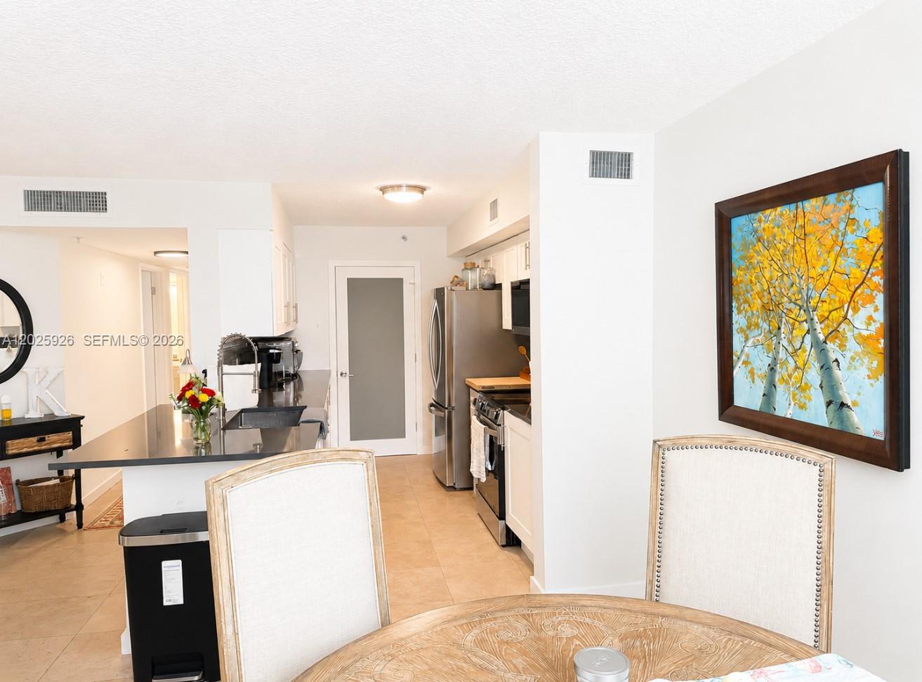 A kitchen with dark countertops and stainless steel appliances opens to a dining area — 3131 Clint Moore Rd # 107, Boca Raton FL 33496, BOCA RATON, FL