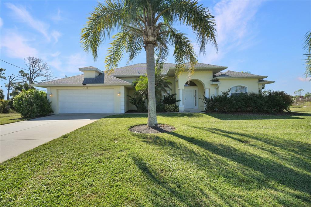 A single-story house with a two-car garage, a palm tree, and a grassy front yard — 1185 ROTONDA CIRCLE, ROTONDA WEST, FL