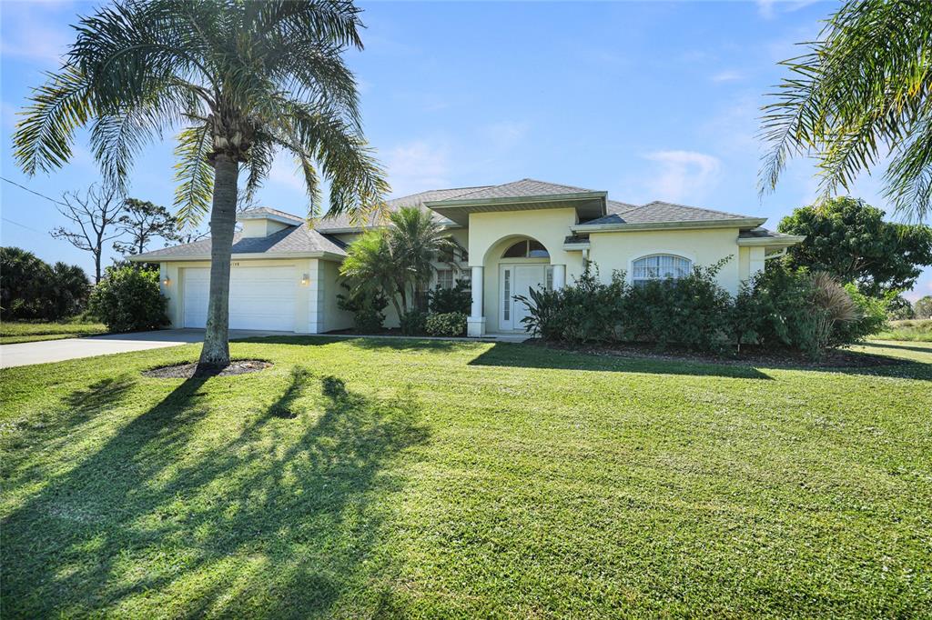 A single-story house with a light-colored exterior, a two-car garage, and a palm tree — 1185 ROTONDA CIRCLE, ROTONDA WEST, FL