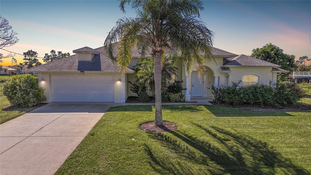 A single-story house with a two-car garage, a palm tree, and a landscaped front yard — 1185 ROTONDA CIRCLE, ROTONDA WEST, FL