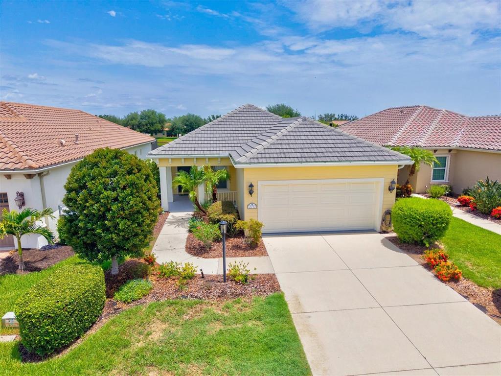 An exterior view of a yellow single-story house with a two-car garage and tile roof — 12717 DEEP BLUE PLACE, BRADENTON, FL