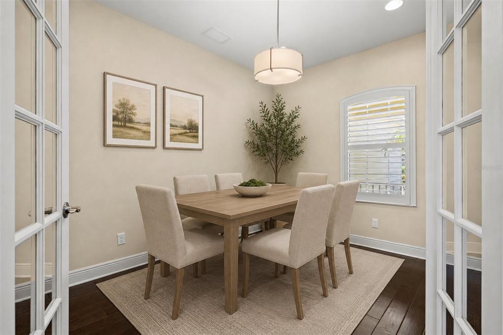 A dining room features a wooden table, six upholstered chairs, a rug, and French doors — 12717 DEEP BLUE PLACE, BRADENTON, FL