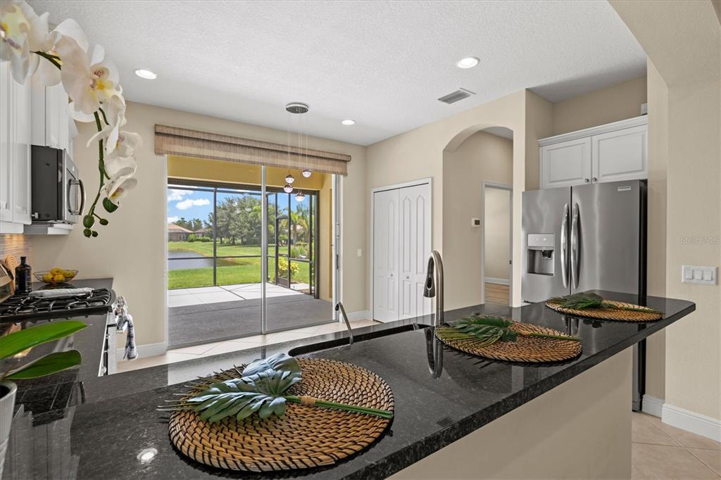 A kitchen with black granite countertops, stainless steel appliances, and a sliding door to a patio — 12717 DEEP BLUE PLACE, BRADENTON, FL