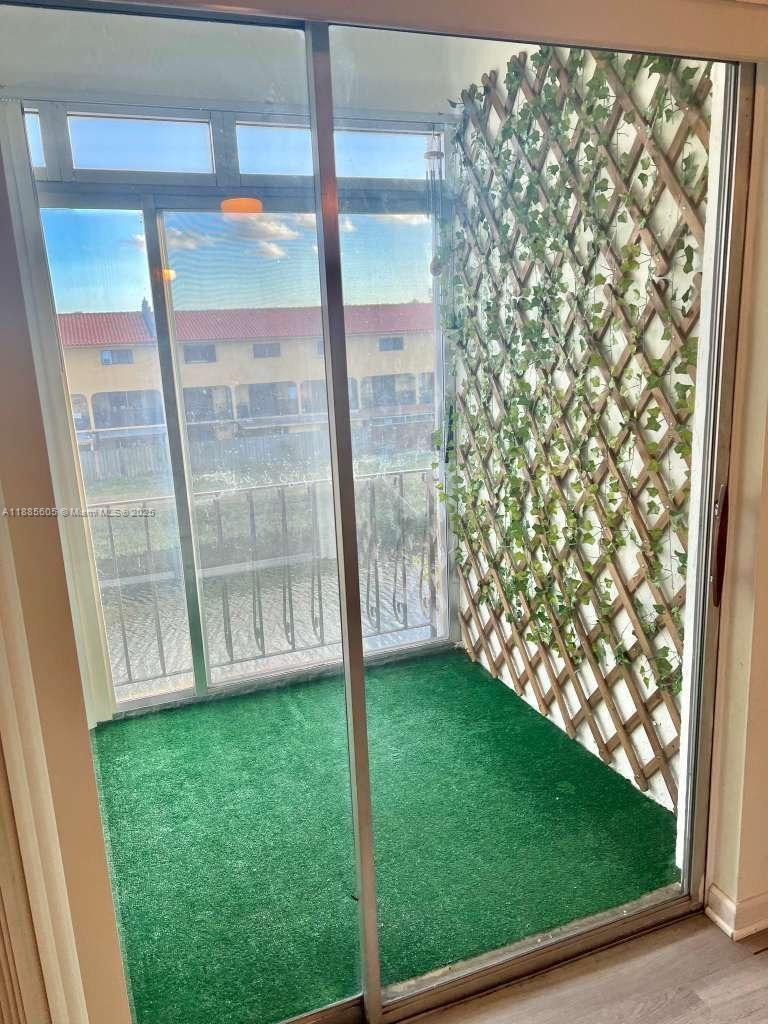 A balcony features artificial grass flooring and a wooden lattice wall covered with faux ivy — 1300 W 53rd St # 18, Hialeah FL 33012, HIALEAH, FL