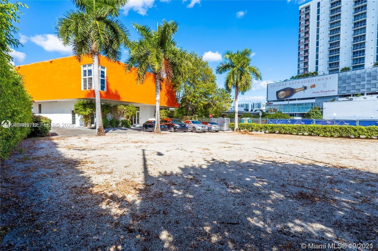 A gravel parking lot sits in front of an orange building with palm trees — 3620 NE Miami Pl, Miami FL 33137, MIAMI, FL