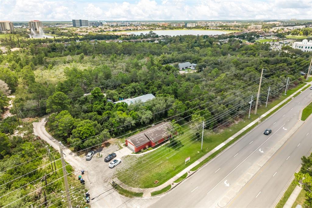 An aerial view shows a red building with a parking area next to a road — 11253 S APOPKA VINELAND ROAD, ORLANDO, FL