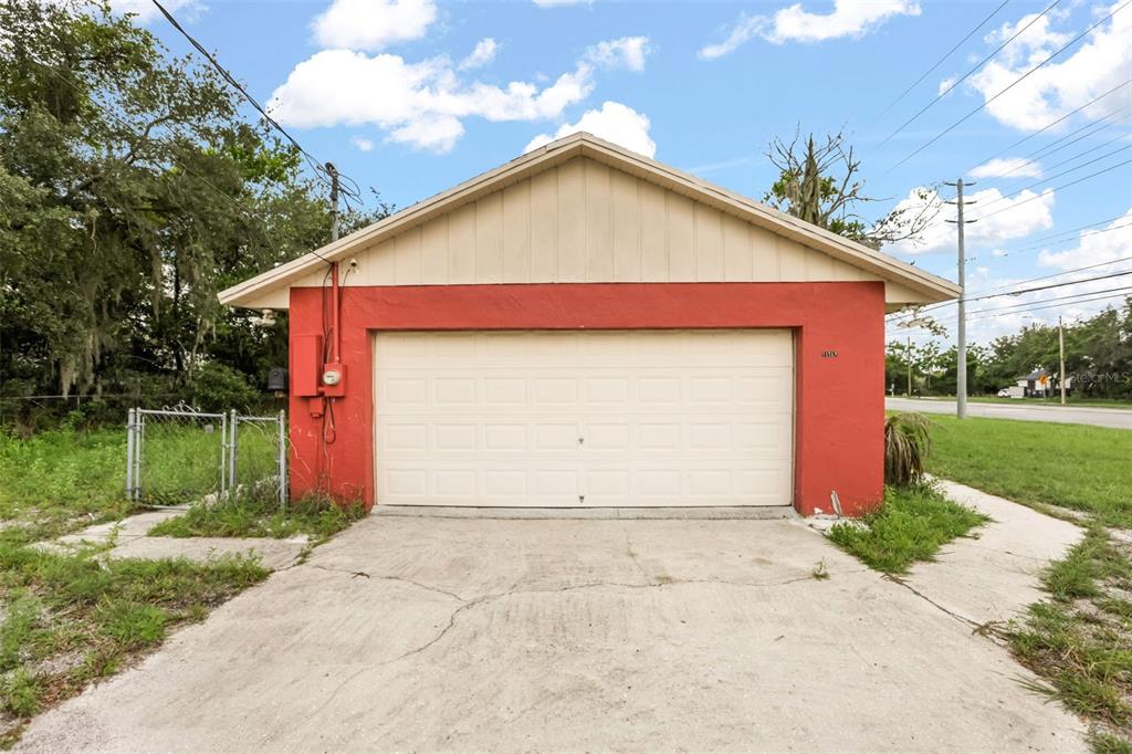 A detached garage with a red stucco exterior and a white sectional door — 11253 S APOPKA VINELAND ROAD, ORLANDO, FL