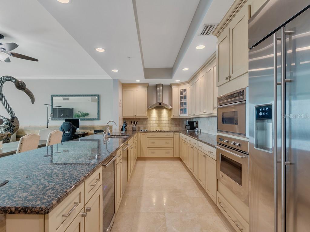 A kitchen with cream cabinets, granite countertops, stainless steel appliances, and light tile flooring — 3135 HIGHWAY A1A UNIT 202, MELBOURNE BEACH, FL