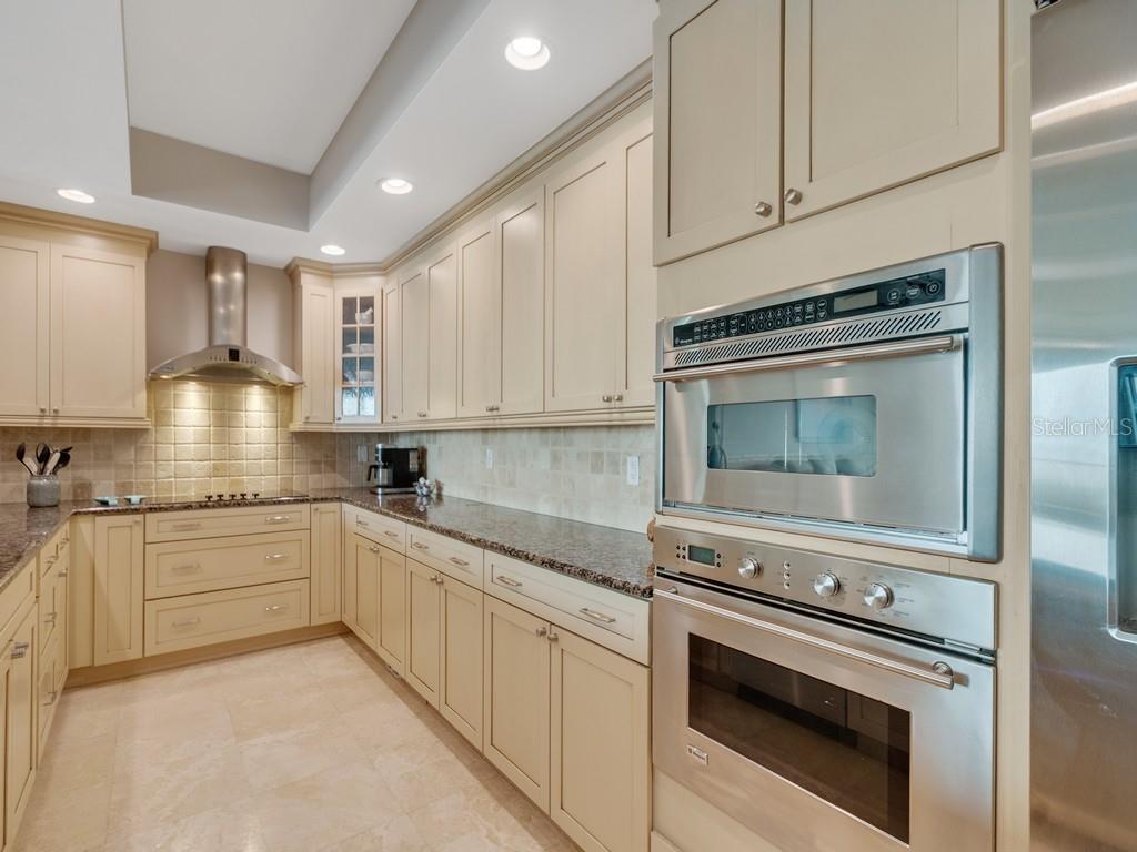 A kitchen with beige cabinets, stainless steel appliances, granite countertops, and a tile backsplash — 3135 HIGHWAY A1A UNIT 202, MELBOURNE BEACH, FL