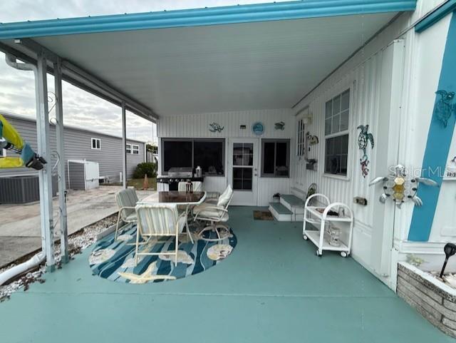 A covered outdoor patio features a dining set, a rolling cart, and coastal wall decor — 1512 23RD AVENUE W, BRADENTON, FL