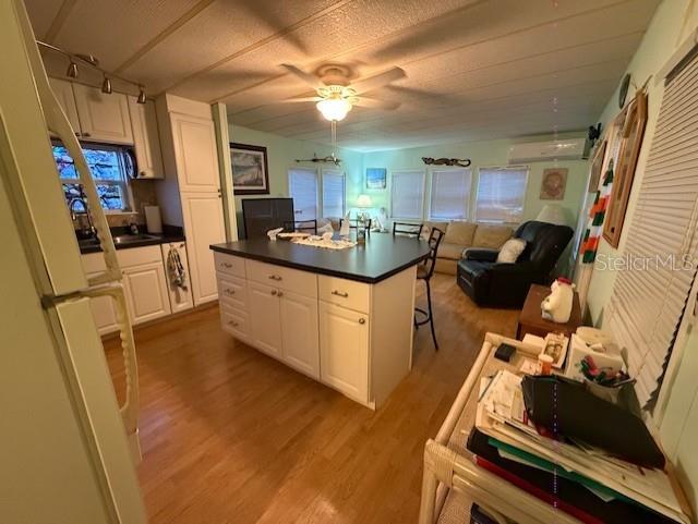 A kitchen with a central island and light wood flooring opens into a living area — 1512 23RD AVENUE W, BRADENTON, FL