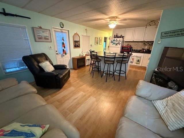 A living room features light wood flooring, a black recliner, and a kitchen island with stools — 1512 23RD AVENUE W, BRADENTON, FL