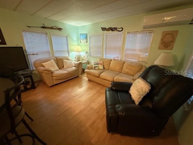 A living room features light-colored walls, wood-look flooring, two sofas, and a black recliner — 1512 23RD AVENUE W, BRADENTON, FL