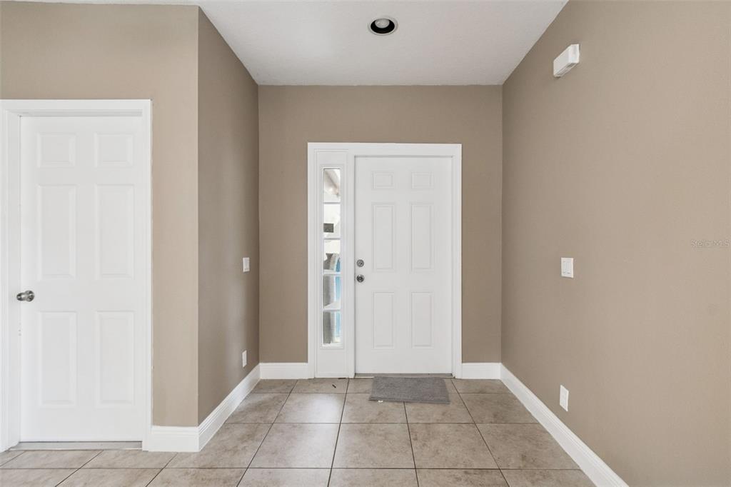 An entryway features tan walls, a white front door with a sidelight, and tiled flooring — 4135 ROCKY FORK TERRACE, ELLENTON, FL