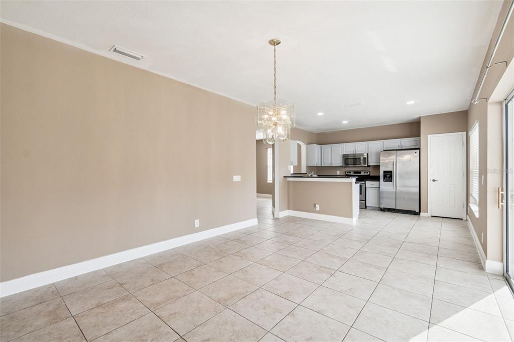 An open-concept dining area with tile flooring leads into a kitchen with stainless steel appliances — 4135 ROCKY FORK TERRACE, ELLENTON, FL