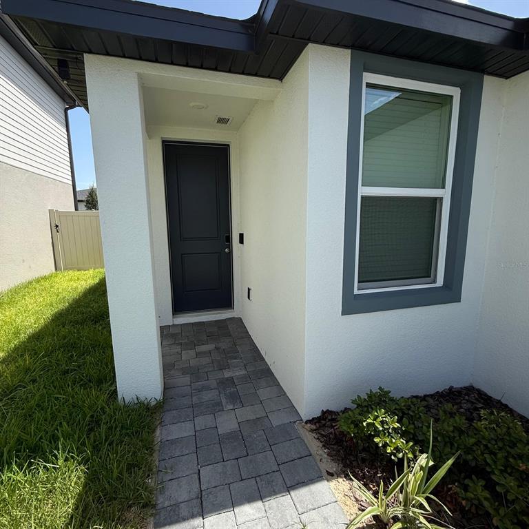 A paved walkway leads to a dark front door under a covered entryway — 5514 CLOVE ROW, HAINES CITY, FL