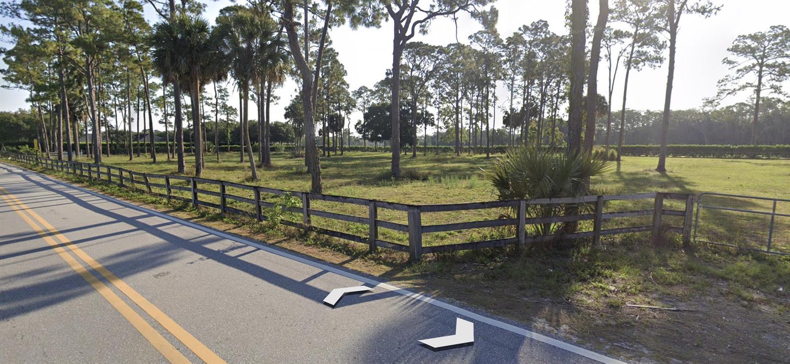 A wooden fence borders a grassy, tree-filled lot along a paved road — 392 F Road, FL 33470, FL
