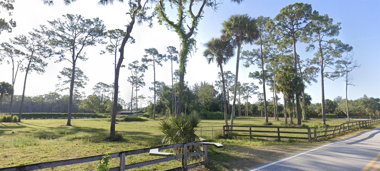 A fenced grassy field with scattered pine and palm trees borders a paved road — 392 F Road, FL 33470, FL