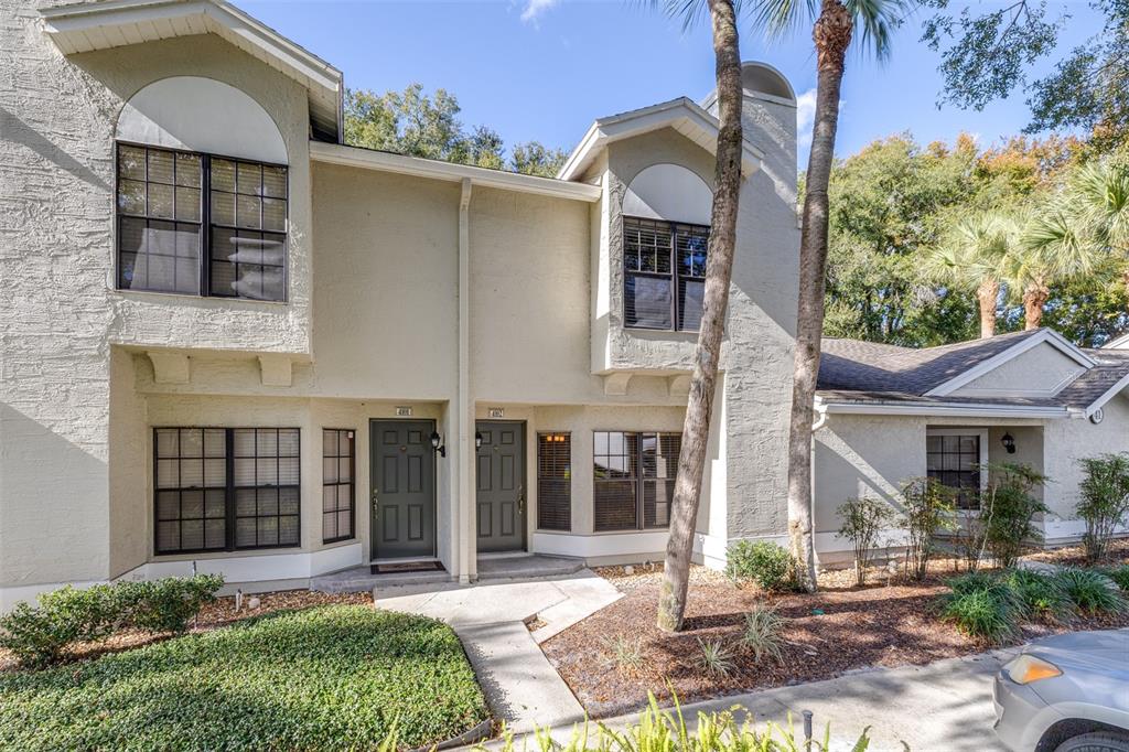 The exterior of a two-story tan stucco townhouse features two dark entry doors and windows — 5100 BURCHETTE ROAD UNIT 4102, TAMPA, FL