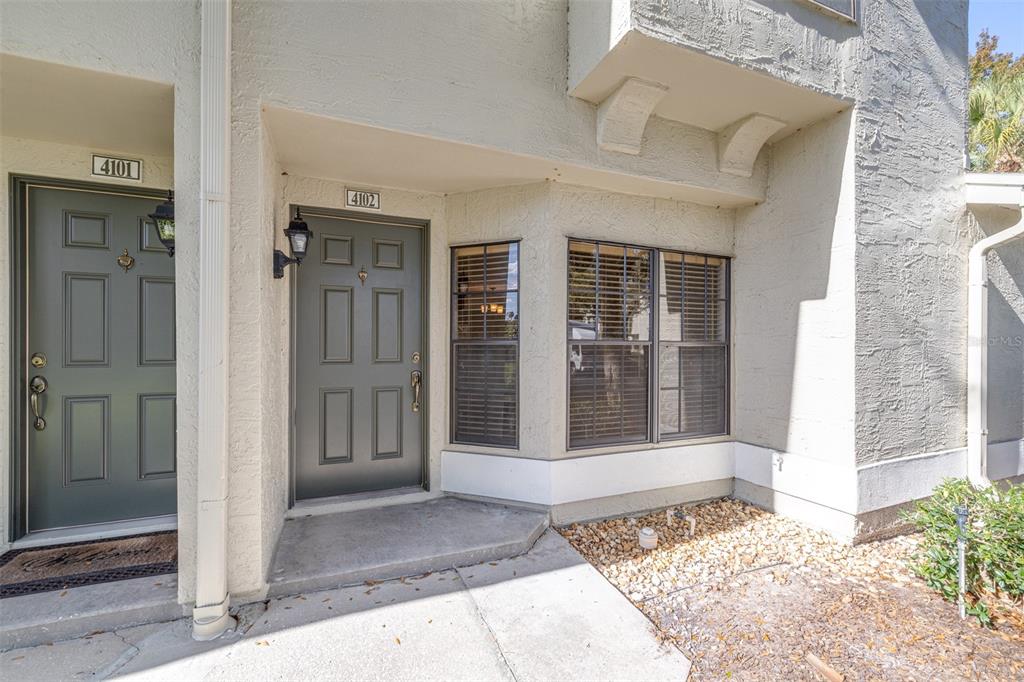 The exterior view shows two adjacent residential front doors with dark green finishes and windows — 5100 BURCHETTE ROAD UNIT 4102, TAMPA, FL
