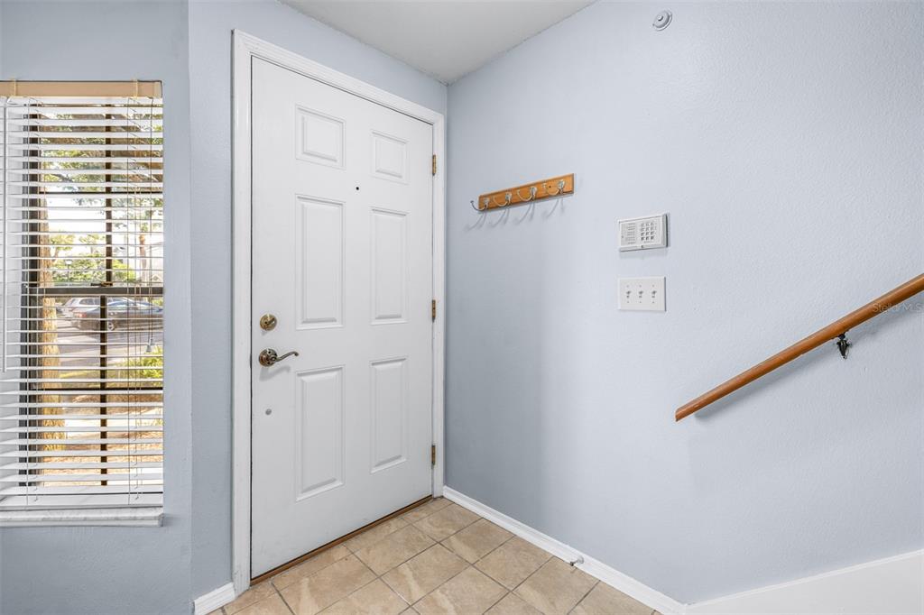 An entryway features a white front door, tiled flooring, a coat rack, and a staircase — 5100 BURCHETTE ROAD UNIT 4102, TAMPA, FL