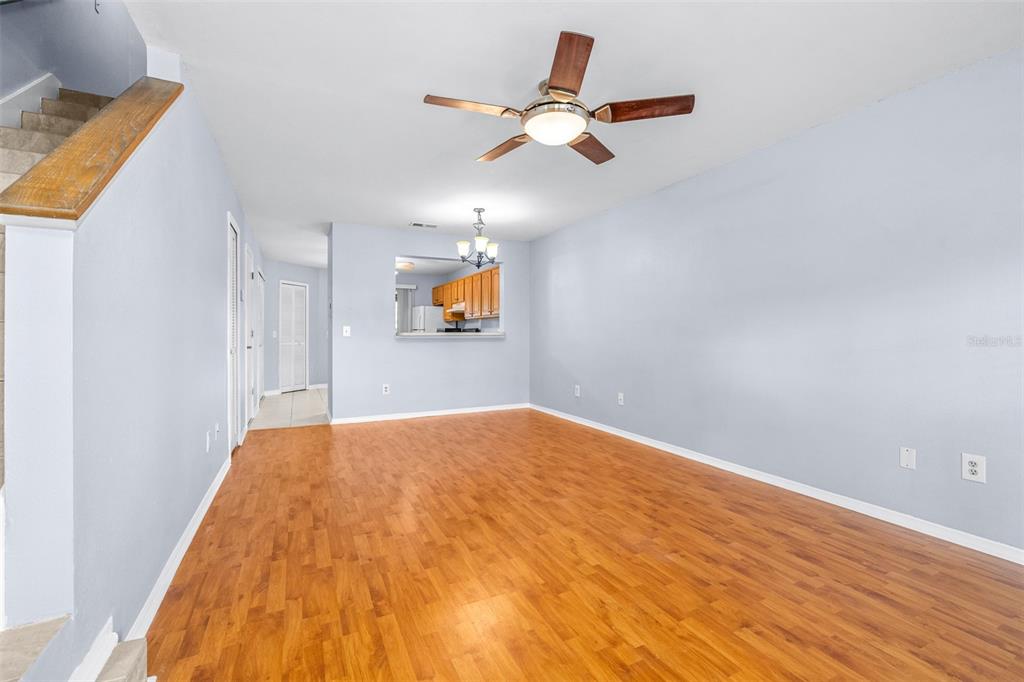 An empty living room features light blue walls, wood-look flooring, and a ceiling fan — 5100 BURCHETTE ROAD UNIT 4102, TAMPA, FL
