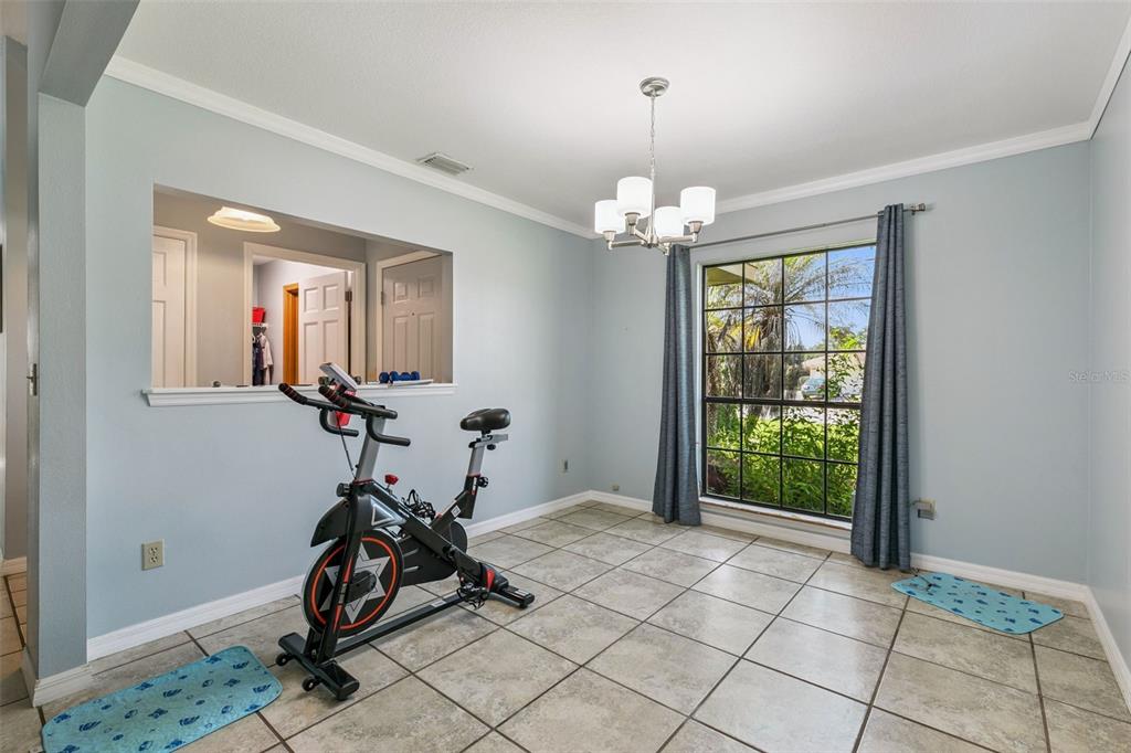 A dining room with light blue walls, tile flooring, a chandelier, and a stationary exercise bike — 4 BASS LAKE DRIVE, DEBARY, FL