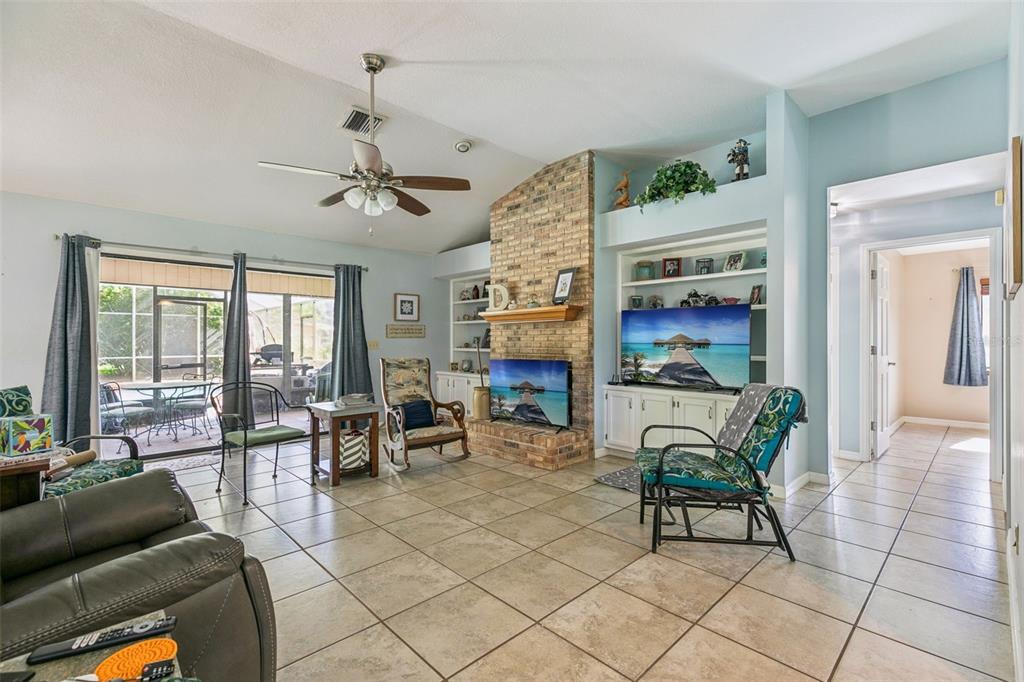 A living room features a brick fireplace, built-in shelving, tile flooring, and a sliding glass door — 4 BASS LAKE DRIVE, DEBARY, FL