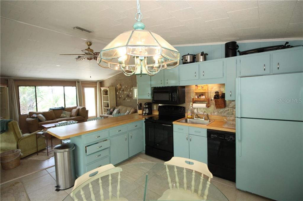 A kitchen with light blue cabinets and a wooden countertop opens into a living area — 9352 LITTLE GASPARILLA ISLAND, PLACIDA, FL