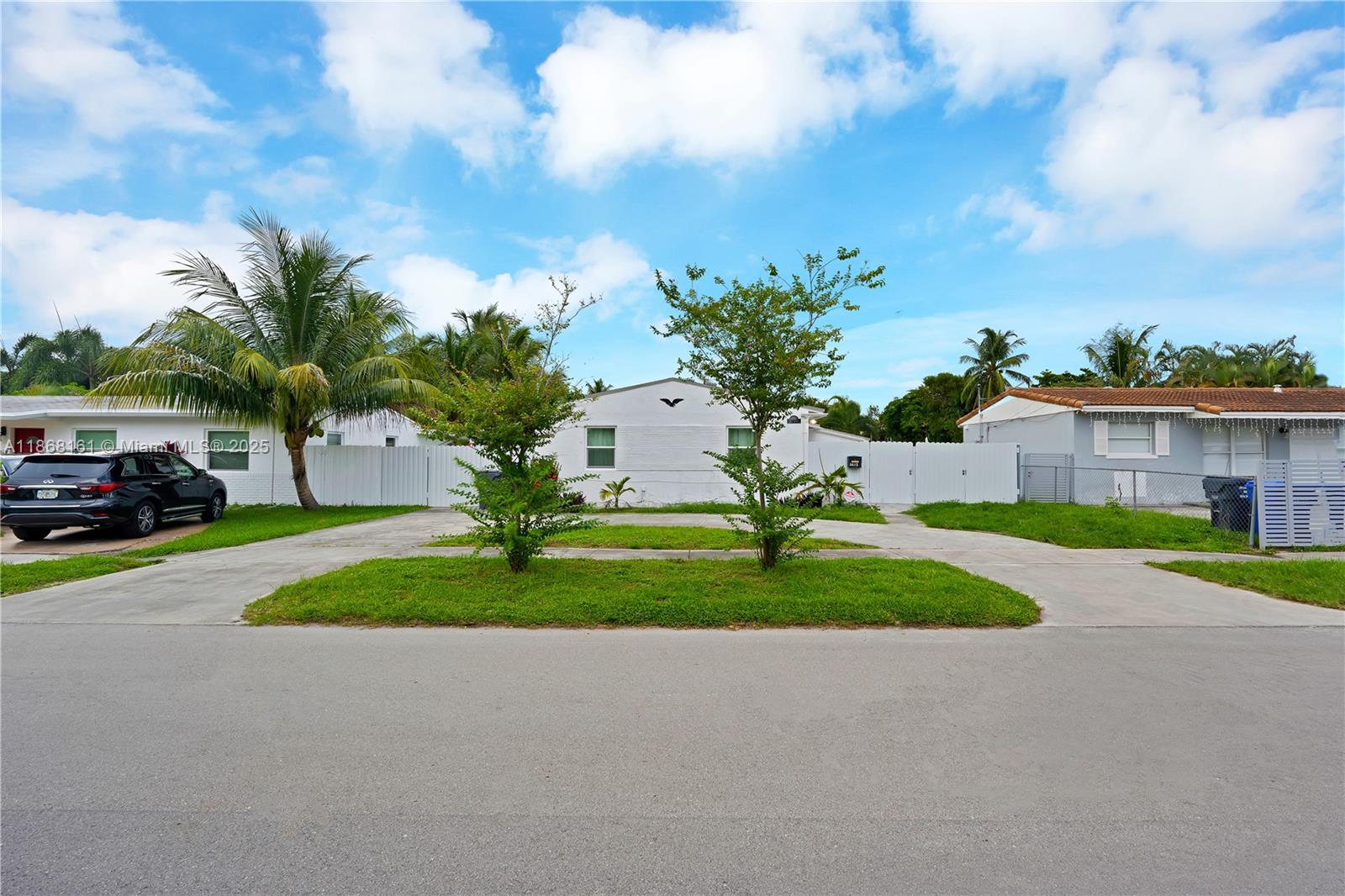 A white single-story house features a paved driveway, two small trees, and a palm tree — 2615 Liberty St, Hollywood FL 33020, HOLLYWOOD, FL