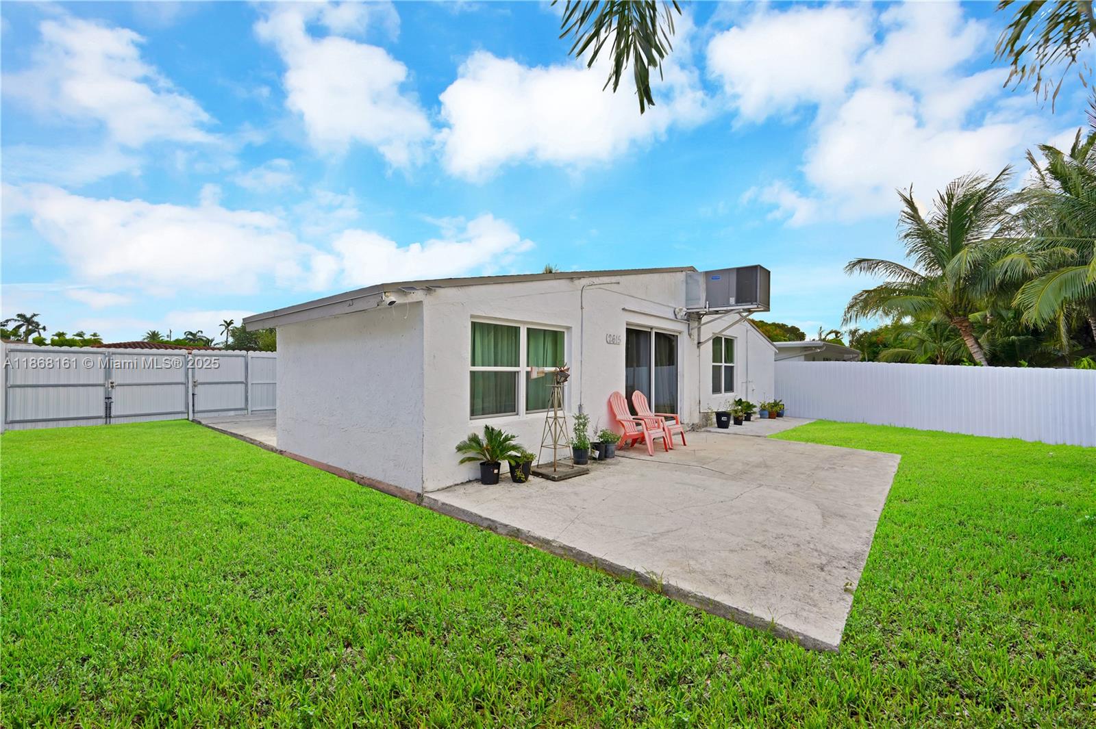 A white house with a concrete patio and a grassy backyard under a blue sky — 2615 Liberty St, Hollywood FL 33020, HOLLYWOOD, FL