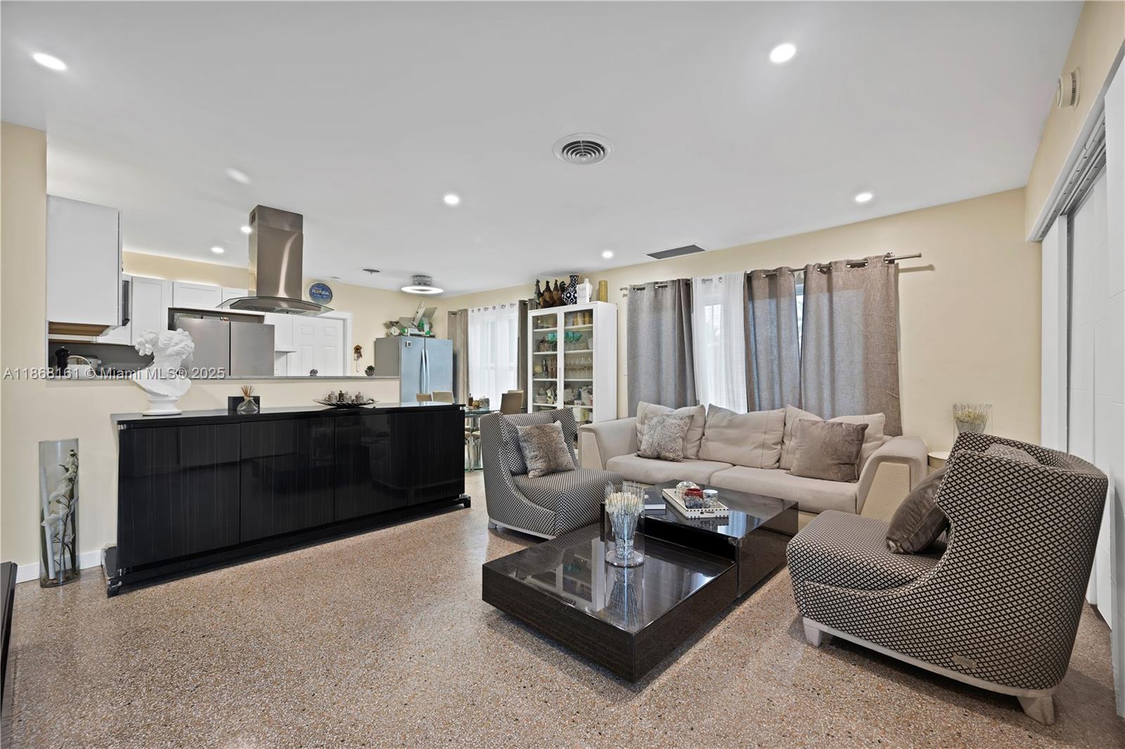 A living room with a black kitchen island, patterned armchairs, and a beige sofa — 2615 Liberty St, Hollywood FL 33020, HOLLYWOOD, FL