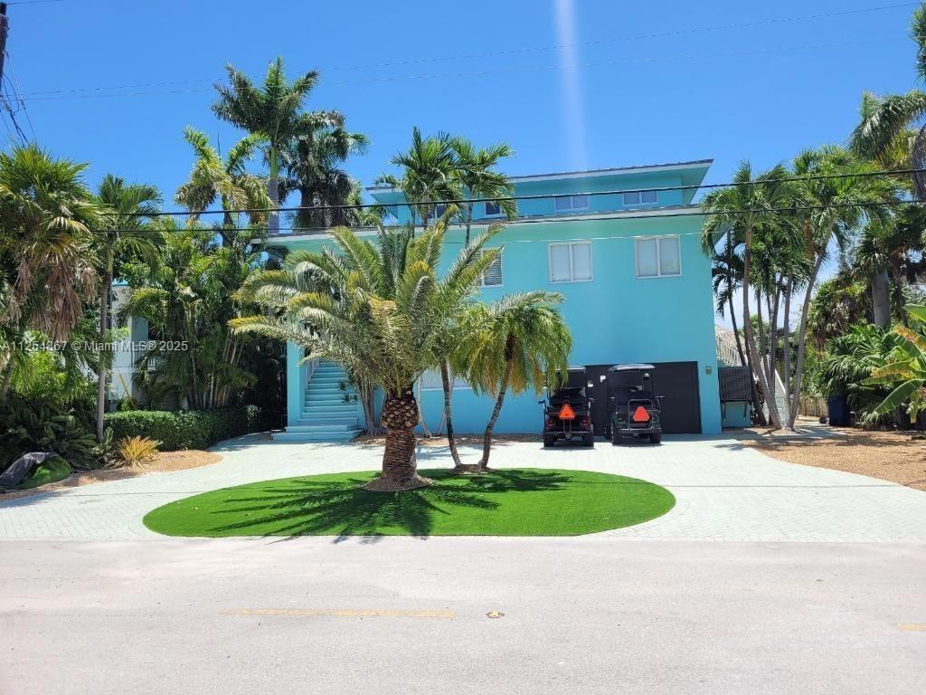 A three-story turquoise house features a paved driveway, a circular lawn, and two golf carts — 124 S Indies, Marathon FL 33050, MARATHON, FL
