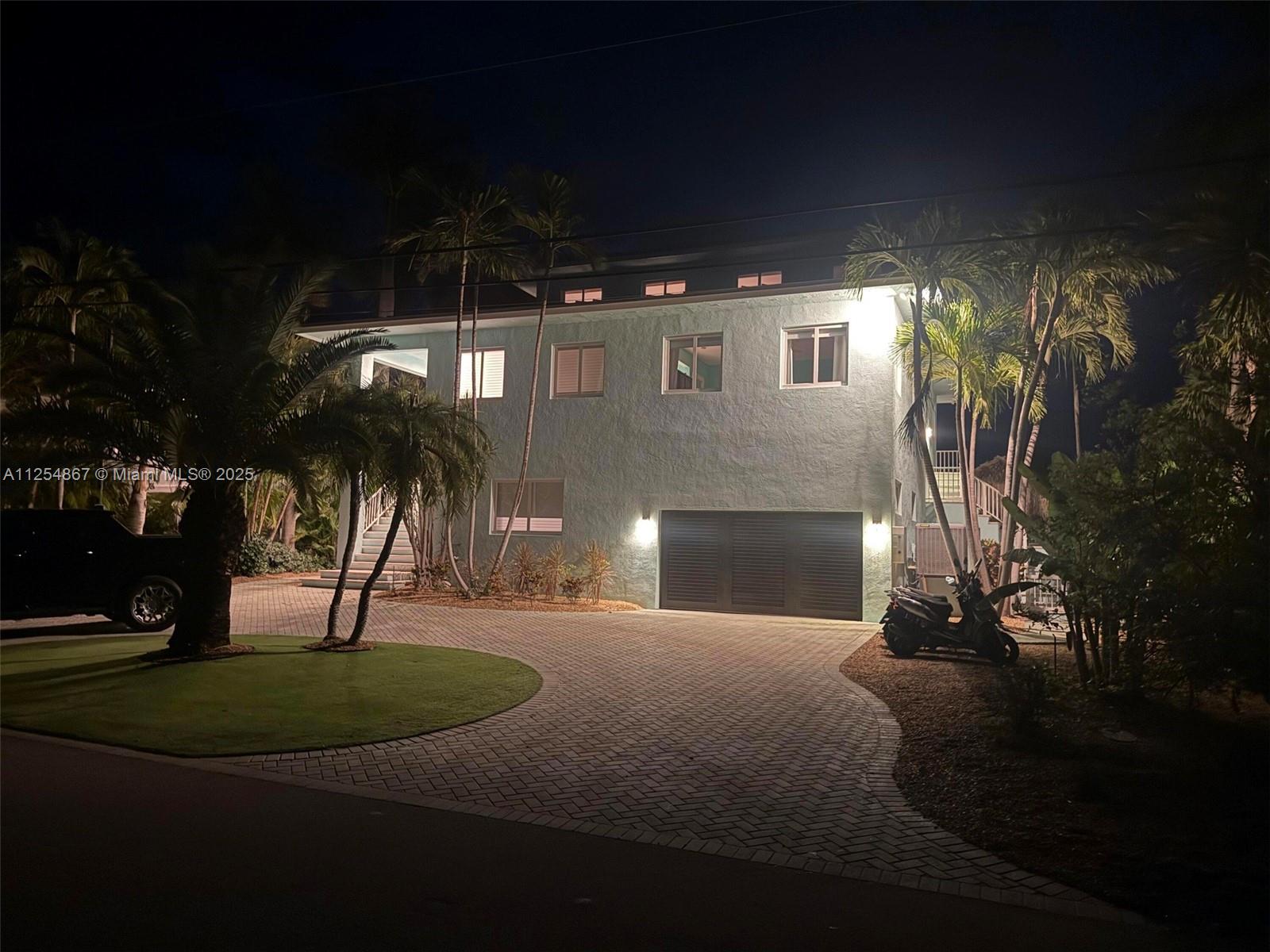 A two-story house with a paved driveway, palm trees, and a garage at night — 124 S Indies, Marathon FL 33050, MARATHON, FL