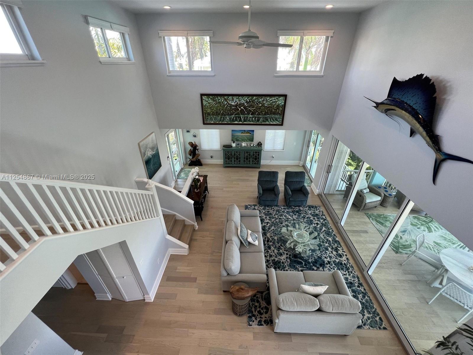 A high-ceilinged living room features a staircase, light wood flooring, and a large wall-mounted fish — 124 S Indies, Marathon FL 33050, MARATHON, FL