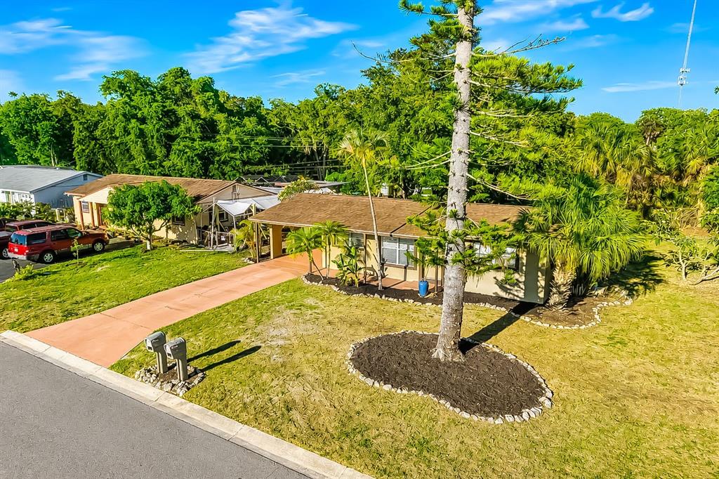 An exterior view of a single-story house with a driveway, lawn, and a large tree — 4219 35TH STREET W, BRADENTON, FL
