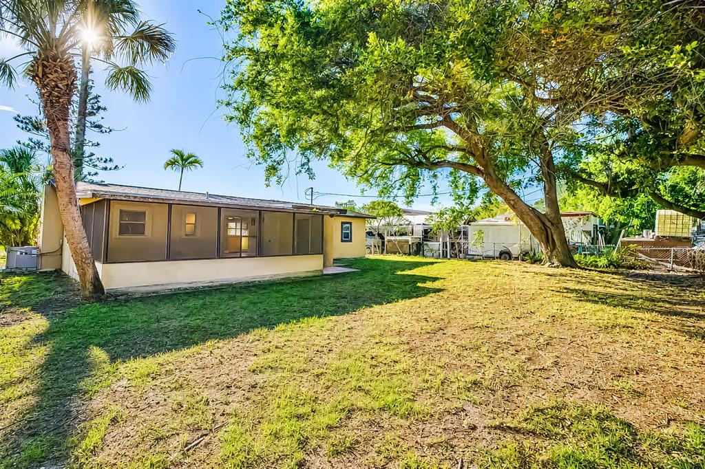 A single-story house with a screened-in porch sits on a grassy lot with large trees — 4219 35TH STREET W, BRADENTON, FL