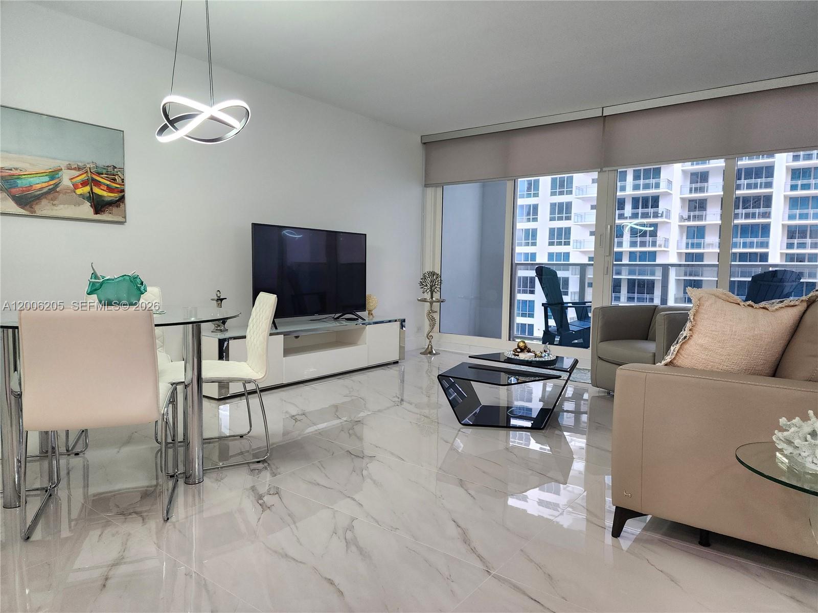 A modern living and dining area features marble floors, a glass table, and balcony views — 3505 S Ocean Dr # 719, Hollywood FL 33019, HOLLYWOOD, FL
