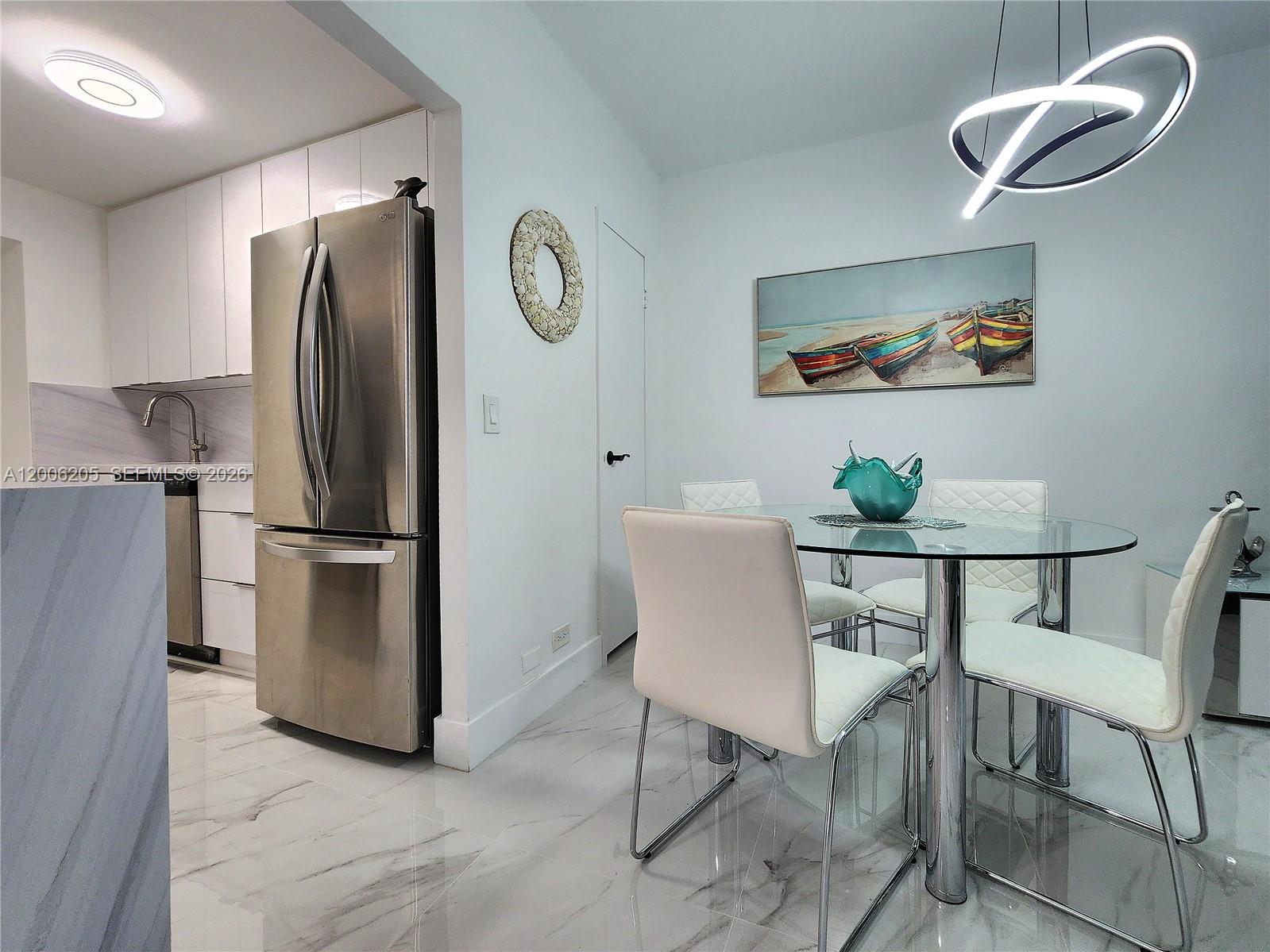 A dining area with a glass table, white chairs, and a modern light fixture — 3505 S Ocean Dr # 719, Hollywood FL 33019, HOLLYWOOD, FL