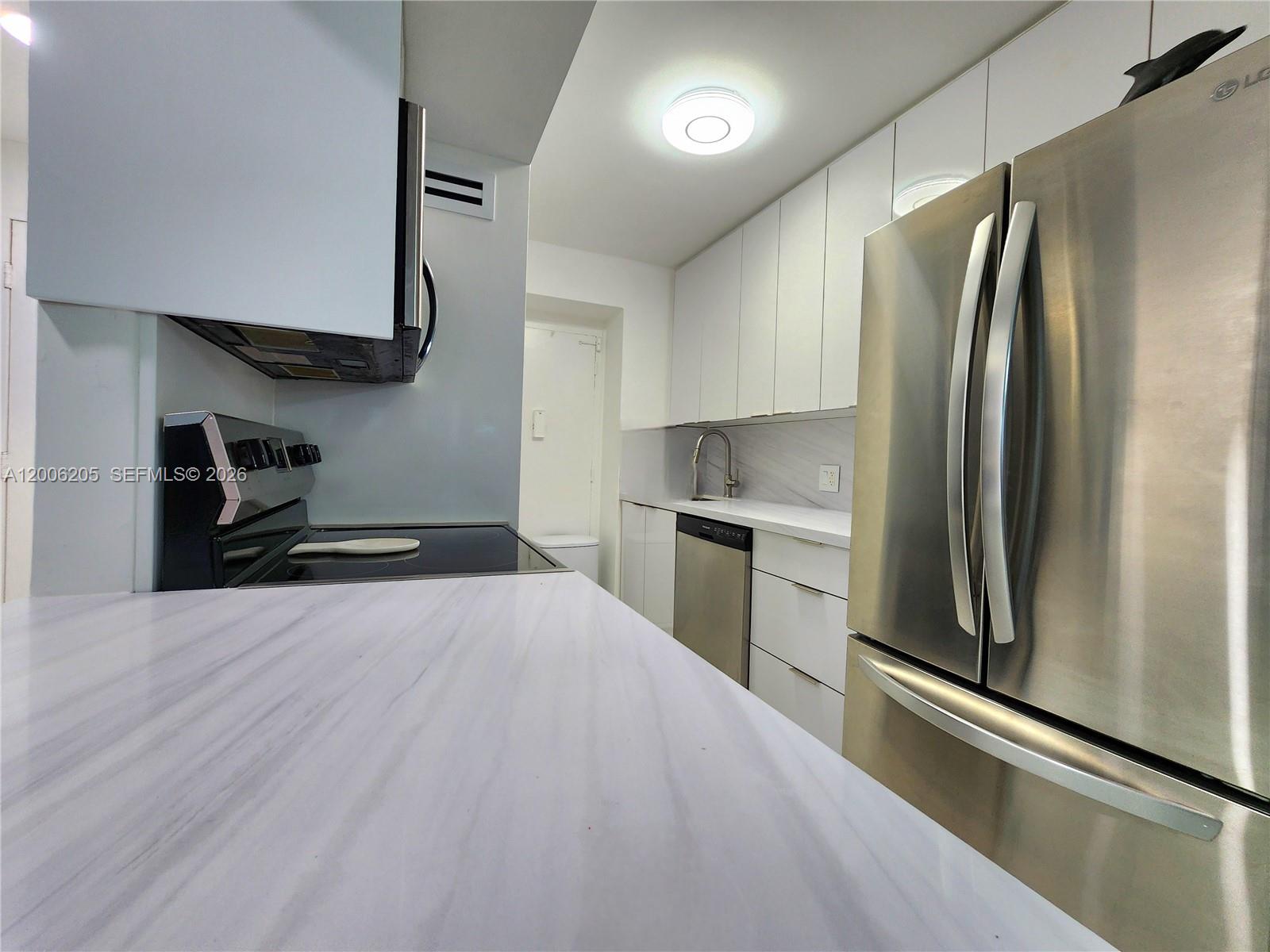 A modern kitchen features white cabinetry, stainless steel appliances, and white marble-patterned countertops — 3505 S Ocean Dr # 719, Hollywood FL 33019, HOLLYWOOD, FL