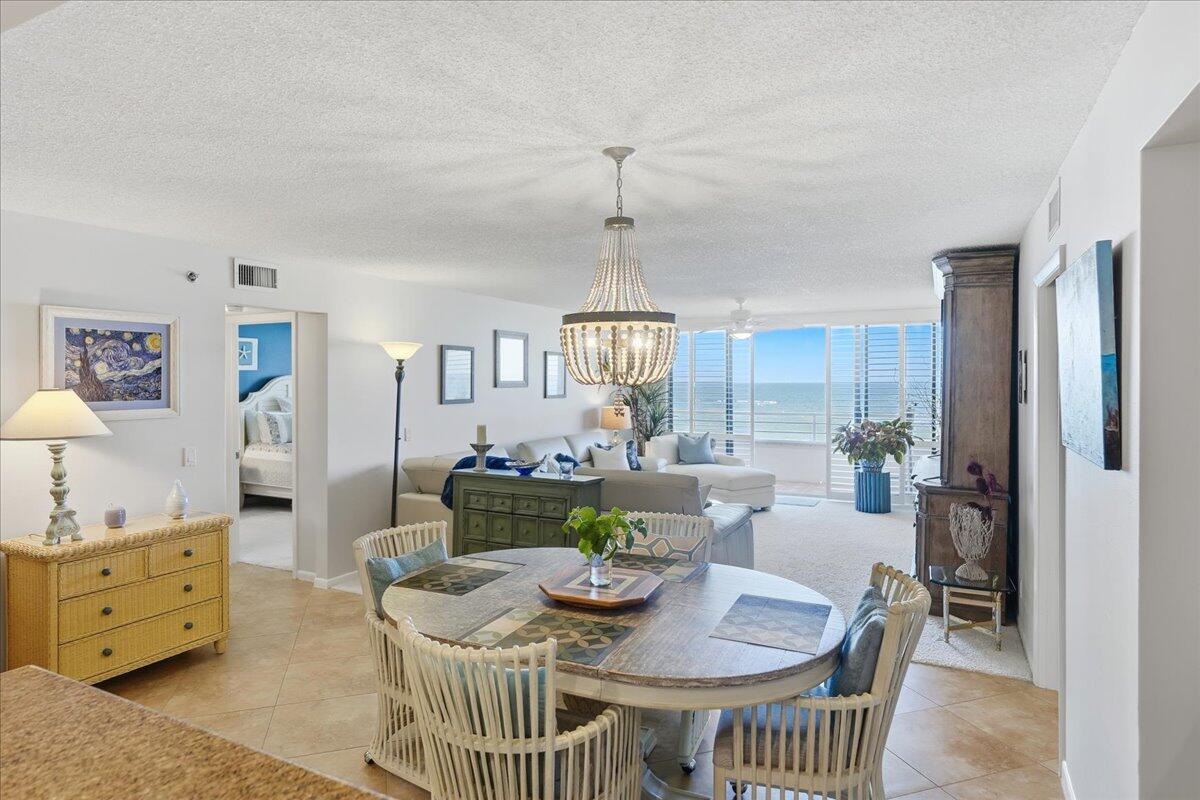 A dining area with a round table leads into a living room overlooking the ocean — 9950 S Ocean Drive # 604, Jensen Beach FL 34957, JENSEN BEACH, FL